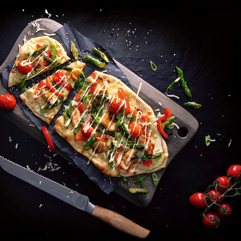 Frisch gebackener Flammkuchen Style Chicken Teriyaki mit knusprigem Boden, zartem Chicken, würziger Teriyaki-Sauce und frischen Toppings auf einem Brett serviert.